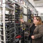 As loud fans blow air to prevent the equipment from overheating, Sofia Kohfield shows some of the equipment that ICOM uses to communicate with the radio towers. This would be replaced with the sales tax money. (Photo by Luisa Loi)