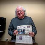 (Photo by David Welton)
Bob Herzberg holds up a 2011 copy of the South Whidbey Record, featuring his police chief retirement article.