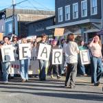 (Photo by Luisa Loi)
Student protesters walk past the Clyde Theatre, holding signs that form the phrase no fear, resist.