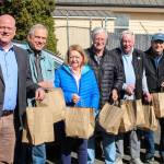(Photo by Luisa Loi)
At left, Reid Schwartz, Jim Slowik, Lyn Bartley, Ken Hulett, Tony Bartley, Dave Williams and Christy Schwartz form a chain to place bags of food inside a car before theyre delivered to schools.