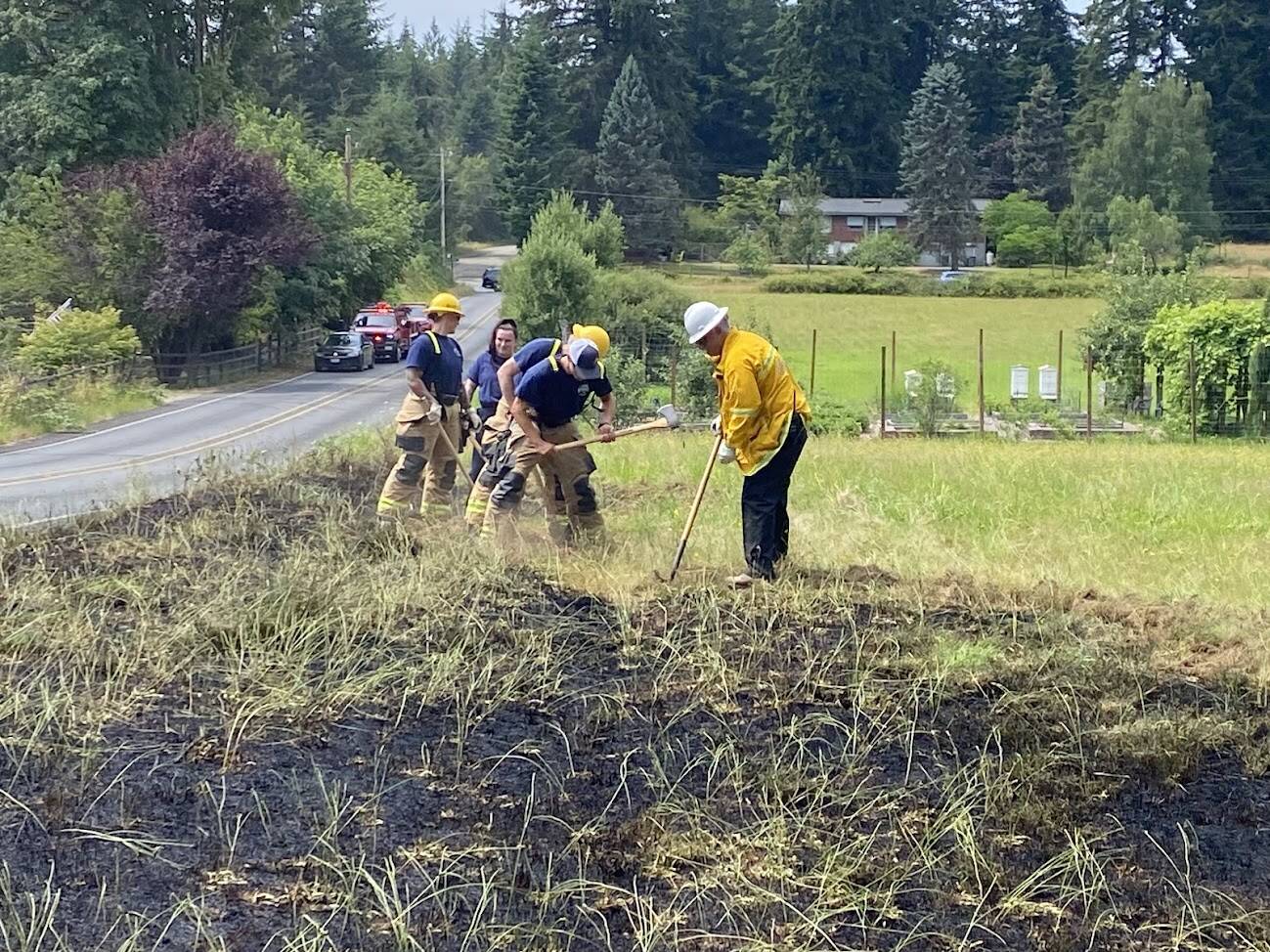 (Photo provided by South Whidbey Fire/EMS) Firefighters cut a line into a brush fire.