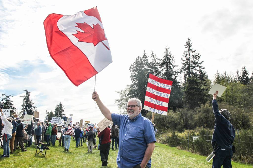 Craig Cyr waves the Canadian flag as a sign of protest in Oak Harbor.