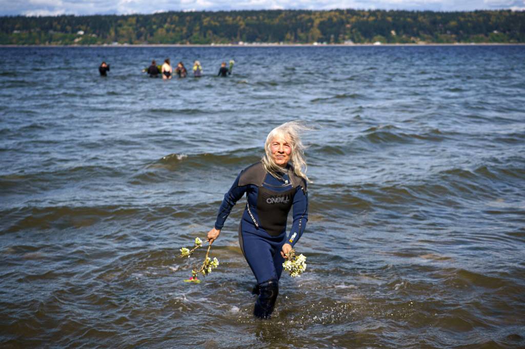 Deborah Koff-Chapin brings some flowers to the water during the waterside ceremony Saturday. (Photo by David Welton)