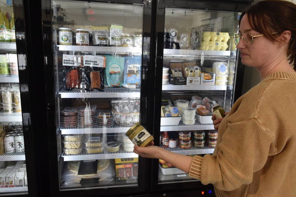 Sometimes customers request a certain product they once tasted by cant remember by name. That sends Whidbey Provisions owner Katie Oakes Stevens off on a foodie scavenger hunt. Here she shows off one such quest, a fermented spicy brown mustard made by OlyKraut of Olympia. (Photo by Patricia Guthrie)