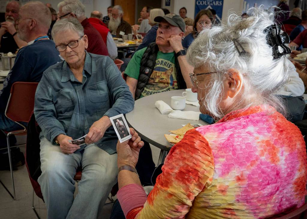 Vicki Robin, right, gazes at a card printed with a photo of Jimmy Scullin as Clarence the angel, from “It’s a Wonderful Life” play at WICA in 2019.