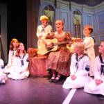 Maria (Karina Andrew) strums the guitar surrounded by the von Trapp siblings. From left are Luna Strong, Hannah Mayne, Lexi Thuet, Cillian Burke, Karina Andrew, Rowan McDonald, Sunny Thuet and Evie Christie. (Photo by Luisa Loi)