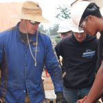 Chris Whiteman helps his students measure the size of their wood panel.
