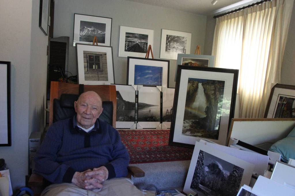 William Schumm smiles among the photographs that adorn his living room (Photo by Marina Blatt)