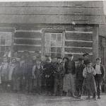 Students stand in front of the log cabin building that was later replaced by the white schoolhouse known today as the Bayview School (Photo courtesy of the Island County Historical Society)