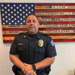 Captain Kevin Barton stands in front of an artistic rendering of the United States flag after getting onboarded to the Oak Harbor Police Department last June (Photo by Jessie Stensland)