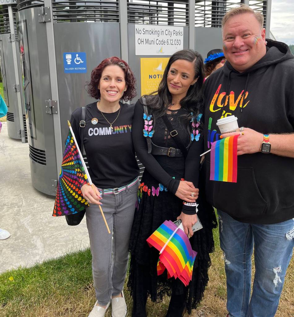 Councilmember Tara Hizon, organizer Ameina Qazi, and Mayor Ronnie Wright celebrate at Flintstone Park before Oak Harbors first Pride Walk. (Photo by Bill Walker)