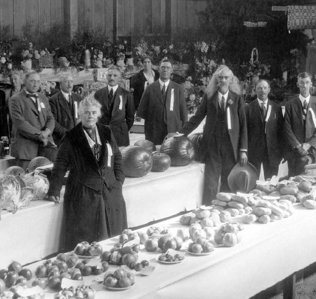 South Whidbey History Museum photo
A historic image shows a 1922 fair in the school gymnasium. The woman in the black dress is Mayor Maggie McLeod. The long-haired man is Paul Cunningham, who was been a wagonmaster, scout and sharpshooter.