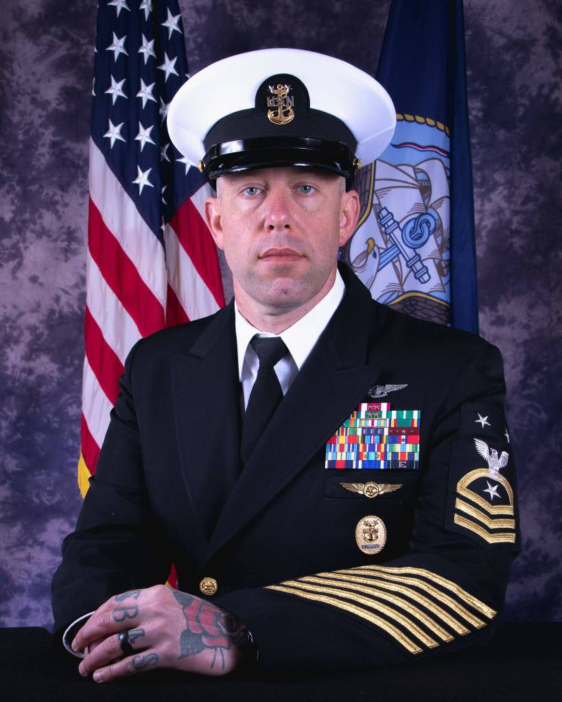 (Photo by Navy) Faulises headshot, featuring a traditional rose tattoo on his hand.