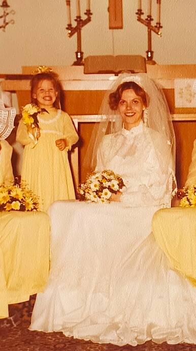 (Photo provided) Benson poses as a flower girl next to her mom in her wedding dress.