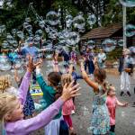 Children chase bubbles blown by Matt Henry.