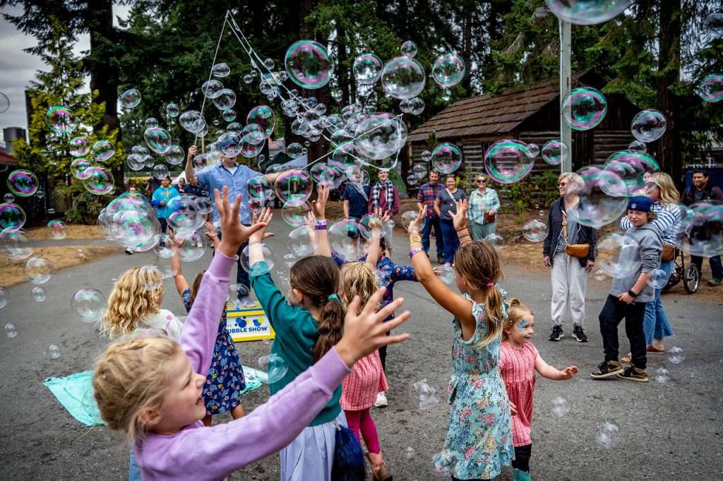 Children chase bubbles blown by Matt Henry.
