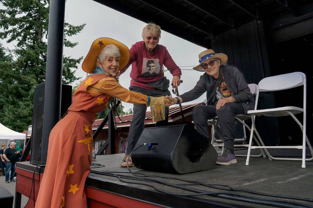 Karen Quest, a performer on stilts, shakes hands with Diane Divelbess, the grand marshal for this years parade.
