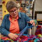 (Photo by David Welton) Danette Sulgrove spreads apart the colorful hand-dyed threads that will be woven.