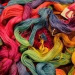 (Photo by David Welton) Yards of colorfully dyed cotton warp – threads that run lengthwise on a loom and are held under tension.