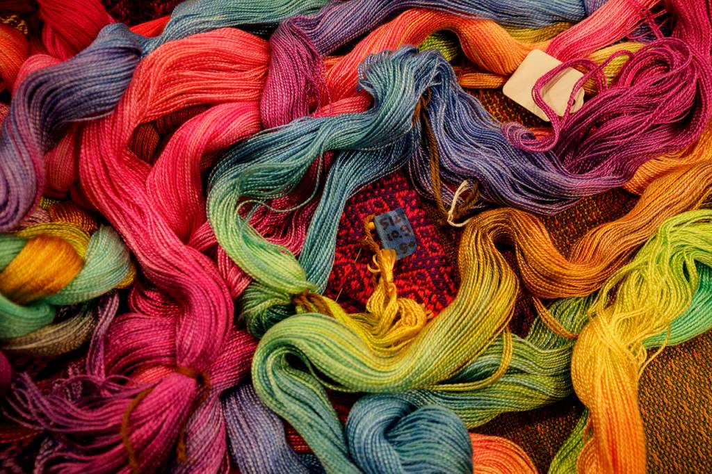 (Photo by David Welton) Yards of colorfully dyed cotton warp – threads that run lengthwise on a loom and are held under tension.
