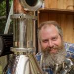 (Photo by David Welton) John Giardina with the shiny still thats responsible for creating Wheyfarer Vodka.
