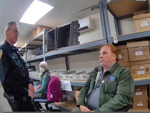 A still image from a police body camera shows Timothy Hazelo with an officer in the ballot counting room.