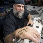 (Photo by David Welton) Bryan has been sewing since he was 18 and has crossed needles on his hand to show for it.