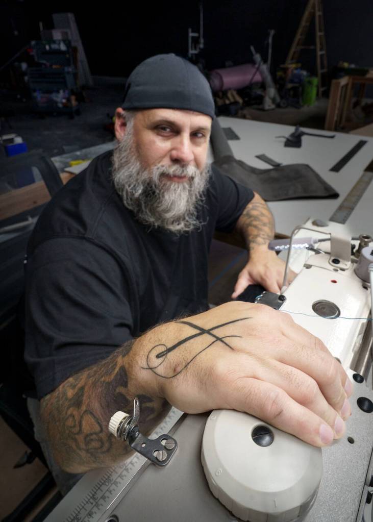 (Photo by David Welton) Bryan has been sewing since he was 18 and has crossed needles on his hand to show for it.