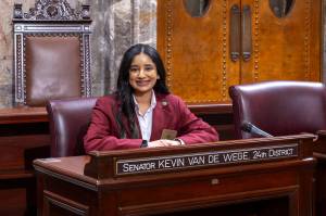 (Photo provided) Aanchal Batwara smiles, seated in the State Capitol in February 2024, where she served as a page for Senator Van De Wege and Senator Lisa Wellman.