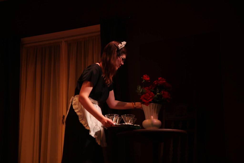 Elizabeth Rud playing Edith arranges flowers on a table. (Photo by Marina Blatt)