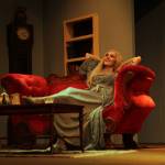 Abby Thuet, playing Elvira, lounges casually on a sofa. (Photo by Marina Blatt)