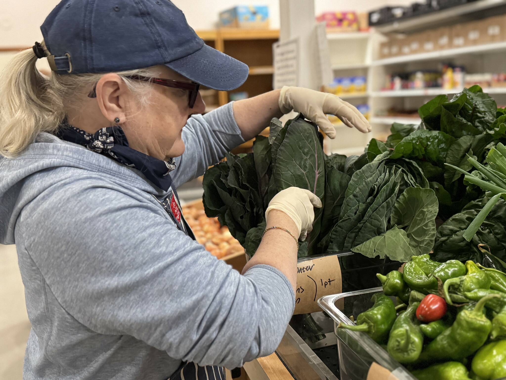 (Photo provided by Good Cheer) A Good Cheer volunteer sorts some leafy greens in the food bank.