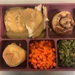 A jail meal includes turkey and gravy with mashed potato, carrot, green beans, cinnamon roll and butter garlic roll.