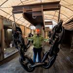 (Photos by David Welton) Senior Recruiter Dane Douglas stands behind a chain of giant, freshly painted links used to anchor massive vessels. Each link weighs a few hundred pounds.