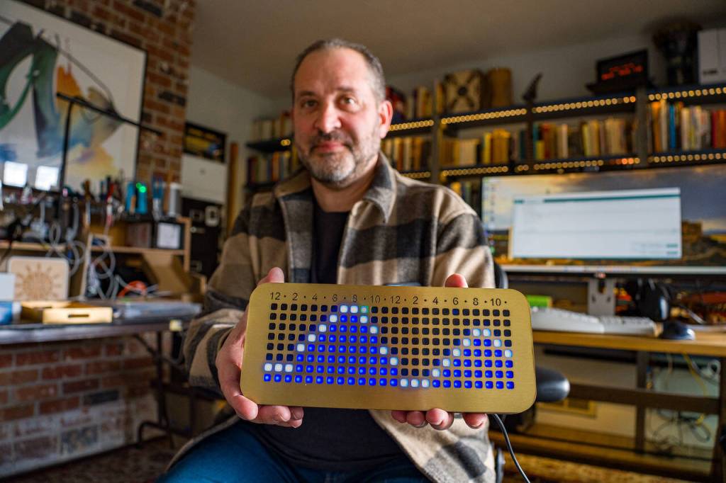 (Photo by David Welton) Dorian Garson demonstrates how the tide clock, called the NautiKron, works. The green dot represents the current hour and the waves show the tides.