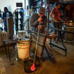 Photo by David Welton. Callahan McVay develops the shape of sea glass floats using snipping tools and heat from the ever-flowing furnace inside Callahans Firehouse Studio in Langley.