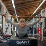 Photo by David Welton. Audie Black, 70, lifts a 6-foot driftwood branch over her head as one of her many strength training exercises.