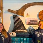 (Photo provided) From left are Heidi Shank and Cindi Rausch in front of their decorated orca fin at the Madrona Supply Company in Clinton.